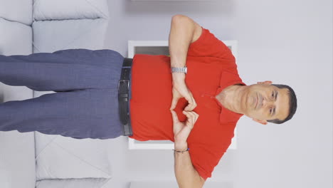 Vertical-video-of-Old-man-making-heart-for-camera.
